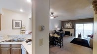 This two-floor residence offers a thoughtfully designed layout that balances comfort and functionality. The main living area is anchored by a classic fireplace framed by a clean white mantel, creating a warm and inviting focal point. A ceiling fan overhead ensures year-round comfort while adding to the room's approachable charm. The living space flows seamlessly into a dedicated dining area, accommodating a full dining set ideal for everyday meals and entertaining alike. Neutral-toned carpeting throughout the living and dining spaces contributes to a soft, cohesive aesthetic. Adjacent to the dining area, the kitchen features light countertops and ample workspace, with an open pass-through that maintains a sense of connectivity between the cooking and living zones. The textured ceiling and neutral wall tones throughout provide a versatile backdrop suited to a variety of interior styles. With two floors of living space, this residence provides room for distinct living and private areas, making it a practical and comfortable home. The overall ambiance is welcoming and well-appointed, with functional details integrated throughout.