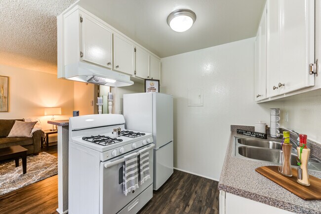 Amplia cocina de concepto abierto con electrodomésticos y pisos de tablones de madera en el Promenade Apartments en Van Nuys, CA - The Promenade