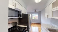 Located at 35 Penataquit Avenue in Bay Shore, NY, this single-floor unit at Mid Island Apartments offers a clean, functional layout with a bright and neutral aesthetic throughout. Gleaming hardwood floors flow seamlessly across the living areas and bedrooms, reflecting natural light and lending warmth to the soft blue-gray wall tones.

The kitchen is well-appointed with white shaker cabinetry featuring brushed nickel hardware, subway tile backsplash, light stone-look countertops, and a full suite of stainless steel appliances including a gas range, over-the-range microwave, and refrigerator. Wood-look flooring grounds the kitchen space.

The living area is generously proportioned, featuring large windows that invite abundant natural light and views of the surrounding neighborhood. A ceiling fan provides added comfort, and baseboard heating runs along the perimeter. A secondary room, suitable as a bedroom or flex space, also features hardwood floors, a window with outdoor views, and baseboard heating.

The bathroom is finished with neutral large-format tile surrounding the soaking tub and shower, complemented by a clean white vanity and wood-look flooring. The overall layout is efficient and well-maintained, making this a comfortable and move-in ready residence in the heart of Bay Shore.