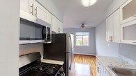 Located at 35 Penataquit Avenue in Bay Shore, NY, this single-floor unit at Mid Island Apartments offers a clean, functional layout with a bright and neutral aesthetic throughout. Gleaming hardwood floors flow seamlessly across the living areas and bedrooms, reflecting natural light and lending warmth to the soft blue-gray wall tones.

The kitchen is well-appointed with white shaker cabinetry featuring brushed nickel hardware, subway tile backsplash, light stone-look countertops, and a full suite of stainless steel appliances including a gas range, over-the-range microwave, and refrigerator. Wood-look flooring grounds the kitchen space.

The living area is generously proportioned, featuring large windows that invite abundant natural light and views of the surrounding neighborhood. A ceiling fan provides added comfort, and baseboard heating runs along the perimeter. A secondary room, suitable as a bedroom or flex space, also features hardwood floors, a window with outdoor views, and baseboard heating.

The bathroom is finished with neutral large-format tile surrounding the soaking tub and shower, complemented by a clean white vanity and wood-look flooring. The overall layout is efficient and well-maintained, making this a comfortable and move-in ready residence in the heart of Bay Shore.