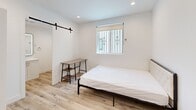 Located at 3001 Van Buren Pl in Los Angeles, CA 90008, this efficiently designed one-bedroom, one-bathroom unit offers a clean, modern aesthetic with thoughtful finishes throughout. The space is laid out on a single floor, making it easy to navigate.

The bedroom is the heart of the unit, featuring light wood laminate flooring that lends warmth to the crisp, all-white walls and ceiling. Recessed lighting provides bright, even illumination, while a window near the entry door allows natural light to filter in. A built-in wardrobe offers ample storage, keeping the room organized and clutter-free. The minimalist design creates a calm, functional environment well-suited for both rest and work.

The bathroom is finished to a high standard, showcasing large-format white wall tiles in the walk-in shower area, complemented by a classic hexagonal mosaic tile floor. A sleek white vanity with an LED-backlit mirror, a towel ring, and a standard toilet complete the space. The consistent use of light wood flooring ties the bathroom seamlessly to the rest of the unit.

Overall, the unit presents a cohesive, contemporary design with a neutral color palette, modern hardware, and quality finishes. Its streamlined layout and practical features make it a functional and comfortable living space in the heart of Los Angeles.