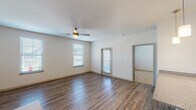 This two-story residence offers two bedrooms and two full bathrooms across a well-designed floor plan. The main living area features rich wood-style flooring, neutral walls, and a ceiling fan, creating a bright and functional space. Multiple windows fitted with blinds allow natural light to fill the room, while a door provides direct access to an exterior entry point.

The kitchen is outfitted with light-toned shaker-style cabinetry extending to the ceiling for ample storage, granite-look countertops, and a full suite of stainless steel appliances including a range, over-the-range microwave, and refrigerator. A peninsula with pendant lighting connects the kitchen to the adjacent living and dining areas.

Both bedrooms are carpeted and include windows that bring in natural light. The bathrooms feature wood-style flooring, granite-topped vanities with undermount sinks, and a tiled tub-shower combination. An attached single-car garage with an automatic opener provides secure parking and additional storage space, accessible directly from the unit. The overall aesthetic is clean, contemporary, and move-in ready.