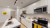 Located at 412 Hunt Club Rd in Blacksburg, Virginia, this modern single-floor residence offers a thoughtfully designed layout with clean lines and contemporary finishes throughout. The open-concept kitchen is a standout feature, showcasing floor-to-ceiling white cabinetry, white quartz countertops, stainless steel appliances including a refrigerator with ice maker, electric range, built-in microwave, and dishwasher. A central island with bar seating adds both functionality and style, while track lighting and recessed lights illuminate the space. Light wood-tone flooring flows seamlessly throughout the unit, creating a cohesive and airy aesthetic. The living area is bright and welcoming, with a large window that invites natural light and provides views of the surrounding neighborhood. Multiple bedrooms offer comfortable, well-proportioned spaces with light-toned walls and resilient flooring, accommodating a variety of living arrangements. The bathrooms are finished with clean white vanities, matching countertops, and light tile flooring. One bathroom features a glass-enclosed walk-in shower, while another provides a combined shower and tub. The overall design is modern and neutral, offering a versatile canvas well-suited for residents in the Blacksburg community.