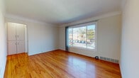 This single-floor, one-bedroom, one-bathroom residence in the Centennial community offers a practical and well-organized layout with consistent hardwood flooring throughout the main living areas. The living room serves as the central gathering space, featuring warm-toned hardwood floors, crown molding, and a large sliding window that allows generous natural light and provides views of the surrounding neighborhood. A second window in the room further brightens the space.

The entry area connects seamlessly to the living room, with multiple closet doors providing convenient storage near the front door. The bedroom is comfortably sized, equipped with a ceiling fan, a large window overlooking greenery, and a built-in closet with shelving, offering functional storage solutions.

The kitchen features light wood cabinetry, tile countertops, a gas range, a full-size refrigerator, and tile flooring, providing all essential appliances in a compact, efficient space.

The bathroom retains a distinctive retro character, with bold blue ceramic wall and floor tiles, a white vanity with overhead cabinetry, and a full bathtub with a shower. A window above the tub adds ventilation and natural light, completing this well-maintained and characterful space.