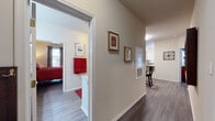 This single-floor residence offers a thoughtfully designed layout connecting several distinct living areas via a central hallway finished with warm hardwood-style flooring and neutral walls accented by decorative framed artwork. The living room serves as the social centerpiece, featuring crown molding, a tiled fireplace, and sliding glass doors that invite natural light and provide outdoor views. Adjacent to the living room, the dining area accommodates a round table with ample space and is enhanced by a large wall mirror that adds depth to the room.

The kitchen is well-equipped, showcasing white shaker-style cabinetry, granite countertops, grey subway tile backsplash, and stainless steel appliances, including a range and dishwasher. A breakfast bar provides additional prep and seating space.

The bedroom is generously sized, benefiting from multiple windows with outdoor views, hardwood-style flooring, and access to a full bathroom featuring white cabinetry with granite countertops and a shower-tub combination. A dedicated walk-in closet with wire shelving provides organized storage. A separate in-unit laundry room houses a full-sized washer and dryer with additional wire shelving above, offering practical convenience throughout the home.