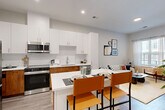Located at 5851 Columbia Pike in Falls Church, VA, this well-appointed one-bedroom, one-bathroom residence offers a thoughtfully designed open-concept layout across a single floor. The modern kitchen is a standout feature, showcasing two-tone cabinetry with crisp white upper cabinets and warm wood-toned lower cabinets, a suite of stainless steel appliances, and a white quartz peninsula with bar seating — ideal for casual dining and entertaining. Light wood-look flooring flows throughout, complementing the clean, neutral palette of the interior. The living room is bright and inviting, benefiting from a large window that brings in natural light and connects the space to the outdoors. The spacious bedroom provides a comfortable retreat, complete with a window, closet access, and a calm, neutral ambiance. The bathroom features a warm wood vanity with white quartz countertop, a large mirror, and a tiled walk-in shower, maintaining a clean and contemporary aesthetic. Additional features include in-unit laundry, two closets, a hallway, an entrance foyer, and a private balcony — offering valuable outdoor space. The overall design is cohesive and modern, blending functional living with stylish finishes throughout.