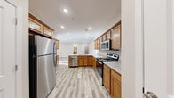Located at 4229 Mel Smith Rd in New Albany, Indiana, this single-floor home offers a thoughtfully designed open layout with modern finishes throughout. The kitchen serves as the heart of the home, showcasing warm honey-toned cabinetry, granite countertops, and a full suite of stainless steel appliances including a refrigerator, range, microwave, and dishwasher. A central island with an undermount sink adds both function and style, creating a natural gathering space that flows seamlessly into the adjacent living area. The living room is bright and generously sized, featuring light wood-look flooring, recessed lighting, a ceiling fan, and glass French doors that open to an outdoor area, filling the space with natural light. The bedrooms are carpeted for comfort, each equipped with ceiling fans and windows that bring in soft, diffused light. Two bathrooms serve the home with matching granite-topped vanities and wood cabinetry; one includes a soaking tub while the other features a walk-in shower. Consistent warm-toned walls, wood-look flooring in the main areas, and clean white trim tie the entire home together in a cohesive, move-in-ready aesthetic.