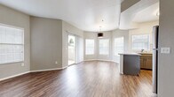This single-floor residence offers a thoughtfully designed open-concept layout that seamlessly connects the living, dining, and kitchen areas. The main living space features rich wood-style flooring and vaulted ceilings that lend a sense of openness and volume. Multiple windows dressed with blinds flood the interior with natural light, while a sliding glass door leads directly to a private covered balcony with views of the surrounding neighborhood greenery.

The kitchen is well-equipped with gray shaker-style cabinetry, light quartz countertops, a classic white subway tile backsplash, and a full suite of stainless steel appliances including a refrigerator, range, microwave, and dishwasher. A breakfast bar peninsula provides additional counter space and casual seating, connecting the kitchen to the living area.

The bedrooms feature plush wall-to-wall carpeting, ceiling fans, and ample natural light from large windows. The bathroom is finished with an extended quartz vanity countertop, gray cabinetry, a large framed mirror, and wood-style flooring, creating a clean and modern aesthetic throughout. Neutral gray-toned walls tie the entire residence together for a cohesive and contemporary feel.