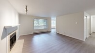 Located in Kent, WA, this 2-bedroom, 2-bathroom residence offers a functional and comfortable single-floor layout. The open living room features light hardwood-style flooring, a fireplace, track lighting, and large windows that invite natural light and offer views of the surrounding greenery. A private balcony extends the living space outdoors.

The kitchen is well-appointed with rich dark wood cabinetry, granite-style countertops, a full suite of appliances including a refrigerator, electric range, and dishwasher, and a convenient built-in pantry with open shelving for added storage.

Both bedrooms are carpeted for comfort and feature neutral tones and natural light. The spacious primary bedroom includes a sliding-door closet, while the second bedroom also provides ample room and a window with a baseboard heating unit. A dedicated closet offers additional storage elsewhere in the unit.

The two bathrooms are finished consistently, each featuring a tub-shower combination with built-in shelving, light hardwood-style flooring, and one bathroom includes a dark wood vanity with a granite-style countertop. Clean, white finishes throughout give both bathrooms a bright and tidy feel. Baseboard heating is present throughout the residence.