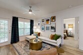 Located at 138 Greison Trail in Newnan, Georgia, this thoughtfully designed 2-bedroom, 2-bathroom residence offers comfortable single-floor living with a cohesive, modern aesthetic throughout. The open-concept layout seamlessly connects the living room, dining area, and kitchen, creating an inviting and functional common space. The living room features crown molding, wood-look flooring, a ceiling fan, and large windows that flood the space with natural light and offer views of lush greenery through the balcony access. The kitchen is well-appointed with white cabinetry, granite countertops, stainless steel appliances, a tile backsplash, track lighting, and a generous island with bar seating — ideal for both cooking and entertaining. The adjacent dining area provides a dedicated space for meals, accented by crown molding and stylish finishes. The primary bedroom is a comfortable retreat with plush carpeting, a ceiling fan, and a walk-in closet with wire shelving. The bathrooms include tiled tub-shower combinations for practicality. Additional highlights include three closets for ample storage, a dedicated laundry area with full-size washer and dryer connections, a utility room, and a private balcony. The entrance features an arched architectural detail that adds a classic touch to the overall design.
