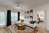 Located at 138 Greison Trail in Newnan, Georgia, this thoughtfully designed 2-bedroom, 2-bathroom residence offers comfortable single-floor living with a cohesive, modern aesthetic throughout. The open-concept layout seamlessly connects the living room, dining area, and kitchen, creating an inviting and functional common space. The living room features crown molding, wood-look flooring, a ceiling fan, and large windows that flood the space with natural light and offer views of lush greenery through the balcony access. The kitchen is well-appointed with white cabinetry, granite countertops, stainless steel appliances, a tile backsplash, track lighting, and a generous island with bar seating — ideal for both cooking and entertaining. The adjacent dining area provides a dedicated space for meals, accented by crown molding and stylish finishes. The primary bedroom is a comfortable retreat with plush carpeting, a ceiling fan, and a walk-in closet with wire shelving. The bathrooms include tiled tub-shower combinations for practicality. Additional highlights include three closets for ample storage, a dedicated laundry area with full-size washer and dryer connections, a utility room, and a private balcony. The entrance features an arched architectural detail that adds a classic touch to the overall design.