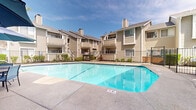 Located at 7971 Rush River Dr in Sacramento, California, this outdoor amenity space serves as a central gathering hub for the residential community. The focal point is a generously sized swimming pool with clear, blue water and defined lap lanes, surrounded by a smooth concrete deck that provides ample space for lounging and movement. A gated perimeter fence encloses the pool area, ensuring safety and privacy for residents.

Adjacent to the main pool is a dedicated spa and hot tub area, complemented by a compact single-story poolside structure that houses changing or utility facilities. This building features neutral lap siding, white trim, and French-style glass doors that open directly onto the patio. Outdoor lounge chairs are positioned nearby for relaxation.

A covered patio area adjoins the clubhouse building, furnished with umbrella-shaded tables and chairs, offering a comfortable space for outdoor dining and socializing. The entire area is framed by mature, leafy trees that provide natural shade and a lush, green backdrop. The surrounding multi-story residential buildings feature classic wood siding, pitched rooflines, private balconies, and exterior staircases, all oriented toward this shared outdoor space. Together, these amenities create a welcoming, resort-style atmosphere well-suited to Sacramento's warm climate.