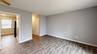 Located at 3716 Groometown Rd in Greensboro, NC, this two-story home offers a practical and well-organized layout across two floors. The main level features wood-look luxury vinyl plank flooring throughout the open living and dining area, which flows seamlessly into a galley-style kitchen equipped with white cabinetry, granite-look countertops, a stainless steel sink, and black appliances including a refrigerator and range. A second kitchen on this level adds notable versatility, complete with its own white cabinetry, sink, and a bright window. A full bathroom on the main floor features a tub/shower combo, white vanity, and wood-look flooring. Upstairs, two carpeted bedrooms provide comfortable retreats, each finished with soft gray walls and ceiling fans for climate comfort. The primary bedroom is generously sized and includes a walk-in closet with built-in shelving. The second bedroom benefits from a large window that brings in natural light. A second full bathroom mirrors the clean, functional design of the first. With seven closets spread throughout and two staircases, storage and accessibility are key strengths of this home.