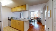 This thoughtfully designed urban residence is spread across a single floor, offering a cohesive and functional layout ideal for city living. The open-concept kitchen and living area serves as the heart of the home, where warm honey-toned cabinetry, granite countertops, and stainless steel appliances define the kitchen space. A peninsula with bar seating provides a seamless transition to the dining area and a bright, airy living room. The living room is anchored by large floor-to-ceiling windows framing dynamic city skyline views, allowing abundant natural light to pour across the classic parquet hardwood flooring. The two bedrooms are each generously proportioned and feature large windows with urban vistas, plush carpeting, and ample natural light. The full bathroom is finished with hexagonal tile flooring, white subway tile accents, a tub-shower combination, and a vanity with medicine cabinet storage. A notable practical feature is the in-unit stacked washer and dryer conveniently located within the bathroom. Clean white walls, consistent warm wood flooring in the main living areas, and city views from nearly every room contribute to a bright, connected, and comfortable atmosphere throughout this well-appointed urban residence.
