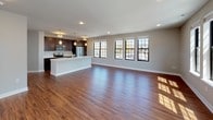 Located on Hamilton Road in Cedarburg, Wisconsin, this single-floor residence offers a thoughtfully designed open-concept layout with modern finishes throughout. The expansive living area is filled with natural light streaming through large, grid-paned windows with black frames, highlighting the warm hardwood-style flooring that flows seamlessly across the main living spaces.

The kitchen is a standout feature, anchored by a generous island with a white quartz countertop and undermount sink, complemented by rich dark-wood cabinetry, stainless steel appliances — including a French door refrigerator, electric range, and built-in microwave — and pendant lighting overhead.

The bedrooms are carpeted for comfort and each benefit from natural light provided by grid-style windows. The primary bedroom connects directly to a walk-in closet with built-in shelving and an en-suite bathroom featuring dark cabinetry, white quartz countertops, a double undermount sink, and a large framed mirror with vanity lighting. A second full bathroom mirrors the same refined aesthetic with a wide vanity and tall storage tower cabinet.

A dedicated laundry area accommodates a stacked washer and dryer unit, adding everyday convenience. The neutral color palette, consistent finishes, and cohesive design elements throughout create a clean, modern ambiance well-suited to comfortable living in the Cedarburg community.