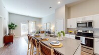 The Chateau presents a thoughtfully designed single-floor residence that seamlessly blends style and functionality. The open-concept layout connects the kitchen and living area, creating an inviting and airy atmosphere enhanced by impressively high ceilings that amplify the sense of space throughout.

The kitchen is a standout feature, outfitted with white shaker cabinetry, quartz countertops, and a full suite of stainless steel appliances including a refrigerator, range, and microwave. A generous island with bar seating serves as both a practical workspace and a natural gathering point, flowing directly into the bright living area. The living room benefits from wood-look flooring, large windows that invite abundant natural light, and direct access to an exterior door.

The bedrooms offer a serene retreat, each featuring plush carpeting, large windows with natural light, and soaring ceilings that enhance the sense of openness. The bathroom is finished with wood-look flooring, white cabinetry, quartz countertops, a large vanity mirror, and a spacious glass-enclosed walk-in shower. Neutral tones and warm accents carry throughout the residence, creating a cohesive and welcoming ambiance from room to room.