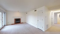 This single-floor residence offers a thoughtfully laid-out living space with a clean, neutral aesthetic throughout. The living room serves as the centerpiece, highlighted by a classic brick fireplace with a white mantle and sliding glass doors that open to an outdoor area, filling the room with natural light. Soft carpet flooring extends throughout the living areas and bedrooms, complementing the bright, white walls.

The kitchen is efficiently designed with dark cabinetry, granite-look countertops, hardwood-style flooring, and black appliances including a range and refrigerator, providing a modern contrast to the rest of the home's neutral palette.

The space includes multiple bedrooms, each carpeted and featuring ceiling fans with light fixtures. The bedrooms are generously sized, with windows that bring in natural light and offer outdoor views. One bedroom provides convenient access to an adjoining bathroom.

Two full bathrooms are present, each featuring a tub-shower combination, tile flooring, a single-sink vanity with wood cabinetry, and a large mirror. The clean, white finishes create a bright and functional atmosphere in both bathrooms.

Overall, this residence combines comfortable, practical living spaces with timeless design elements, offering a welcoming and versatile environment throughout its single level.