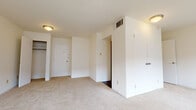 This single-floor residence offers a clean, functional layout designed to maximize usable space throughout. The living area is generously sized, finished with plush light-colored carpeting and crisp white walls that create a bright, open atmosphere. Multiple windows fitted with blinds allow natural light to filter in while offering views of the surrounding exterior.

The bedroom is well-proportioned, also carpeted, and features multiple closet options, including what appears to be a walk-in and an additional standard closet, providing substantial storage capacity. An entry door leads directly into this space, adding a practical layout element.

The galley-style kitchen contrasts the lighter living areas with rich, dark wood cabinetry and dark countertops. It is equipped with a stainless steel range, black refrigerator, dishwasher, and a stainless steel sink, offering a full suite of appliances along dark hardwood-style flooring.

The bathroom continues the dark hardwood-style flooring and features a rich wood vanity with a white countertop, a full-sized soaking tub with a classic square tile surround, and a chrome fixtures throughout, contributing a clean and functional aesthetic to the space.