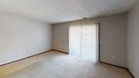 This single-floor residence in West Middlesex, Pennsylvania offers a practical and comfortable layout designed for easy everyday living. The floor plan, as seen in the overhead view, reveals a well-organized arrangement of living, sleeping, kitchen, and bathroom spaces flowing cohesively throughout the home.

The living area is generously proportioned, featuring light-toned carpeting, neutral wall tones, and a textured ceiling. A large sliding glass door dressed with vertical blinds allows natural light to fill the space and provides access to the outdoors. An adjacent area with warm hardwood-style flooring adds visual variety and connects the living space to the rest of the home.

The kitchen is equipped with warm oak cabinetry offering ample storage, dark laminate countertops, a double stainless steel sink, and a black electric range with an overhead ventilation hood — a functional setup suited for everyday cooking.

The bedrooms are carpeted and well-lit, with windows dressed in blinds that bring in natural light. One bedroom features a walk-in closet outfitted with double hanging rods and shelving, providing generous storage capacity. Another bedroom includes a dedicated closet with built-in shelving.

The bathrooms include a full bath with a soaking tub and tiled surround featuring built-in niches, as well as a secondary bathroom with hardwood-style flooring. Throughout the home, dark wood trim provides a consistent finishing detail.