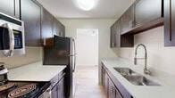 Located in Golden, Colorado, this single-floor residence offers three bedrooms and two bathrooms in a thoughtfully laid-out floor plan. The galley-style kitchen is a standout feature, lined with rich dark espresso cabinetry, light quartz countertops, stainless steel appliances including a refrigerator and dishwasher, and a dual-basin sink with a modern pull-down faucet — all finished with light hardwood-style flooring that flows throughout the main living areas. Two living areas provide flexible space for entertaining or relaxation, with one featuring sliding glass doors that open to a private balcony overlooking colorful, tree-lined surroundings, allowing for ample natural light. The bedrooms are carpeted for comfort and each include ceiling fans, baseboard heating, and windows with views of the surrounding foliage. Closet space is provided in the bedrooms for convenient storage. The two bathrooms offer distinct configurations — one features a full tub/shower combo with clean white surrounds, while the second includes a stylish vessel sink atop a dark wood vanity with modern lighting. Neutral wall tones and textured ceilings complete the warm, functional character of this Golden, CO home.