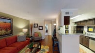 This thoughtfully laid-out one-bedroom, one-bathroom residence in Conroe, Texas presents a functional and stylish single-floor design. The living room features rich hardwood flooring, crown molding, and an earthy olive-green accent wall that creates a warm, inviting ambiance. Natural light filters through the windows, complementing the cozy seating arrangement and decorative touches throughout. Adjacent to the living room, the dining area accommodates a round table with seating for four, anchored by a pendant light fixture and a rich brown accent wall with classic chair rail molding. The galley-style kitchen is well-appointed with dark espresso cabinetry, granite-look countertops, black appliances including a range and refrigerator, and tile flooring. Ample upper and lower cabinet storage lines both sides of the kitchen, maximizing efficiency. The bedroom is a serene retreat, featuring plush carpeting, a ceiling fan, a soothing blue accent wall, and a window that allows natural light to brighten the space. A walk-in closet provides generous storage. The bathroom offers dark wood vanity cabinetry, granite-look countertops, tile flooring, and a shower-tub combination. Throughout the residence, consistent design elements and thoughtful color palettes create a cohesive and comfortable living environment.