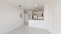 Located at 1451 W 29th St in Hialeah, Florida, this two-bedroom, two-bathroom residence offers a clean, modern aesthetic throughout its efficiently designed single-floor layout. Polished marble-look tile flooring runs seamlessly across all living areas, reflecting natural light and lending an airy, contemporary feel to the entire space.

The open-concept kitchen and living area serves as the heart of the home. The kitchen features light gray cabinetry extending to the ceiling for ample storage, stainless steel appliances including a full-size refrigerator, range, and over-the-range microwave, and a white quartz peninsula with an integrated sink that opens directly to the living area — ideal for both cooking and entertaining.

The living room benefits from a sliding glass door that leads to one of two balconies, filling the space with abundant natural light and outdoor views of the surrounding Hialeah neighborhood. The second bedroom is bright and sun-drenched, with a large window framing outdoor views.

The primary bedroom is a well-proportioned retreat with its own dedicated closet space. Both bathrooms are finished with the same consistent tile flooring and include a tub-shower combination, modern vanity, and clean white walls. A dedicated laundry area and an additional closet round out the practical features of this well-appointed residence.