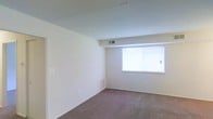 Located at 820 Carvel Drive in Dover, Delaware, this single-floor residence offers a clean, functional layout designed for comfortable everyday living. The interior is finished with neutral, light-toned walls that create a bright and open atmosphere throughout. Wall-to-wall carpeting in a warm, muted tone covers the floors, adding softness and a sense of coziness to the space. A prominent sliding window allows generous natural light to filter in, enhancing the airy quality of the room while providing ventilation. Ceiling-mounted HVAC vents are integrated into the design, ensuring year-round climate control. The space also features baseboard heating for additional warmth during cooler months. The layout is straightforward and efficient, with smooth, clean walls offering ample flexibility for furnishing and personalization. The overall ambiance is understated and move-in ready, with a simple, well-maintained aesthetic that suits a variety of living arrangements. The single-floor configuration ensures easy accessibility and convenient navigation throughout the unit.