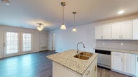 Located at 102 Amerson Orchard Rd in Georgetown, Kentucky, this single-floor residence offers a well-designed, open-concept layout with consistent hardwood-style flooring flowing throughout. The kitchen serves as the heart of the home, showcasing crisp white cabinetry, granite countertops, a tile backsplash, and a full suite of stainless steel appliances including a refrigerator, range, microwave, and dishwasher. A central island with a double basin sink and elegant pendant lighting above adds both function and style, while recessed lighting ensures the space is well-lit. The open layout connects the kitchen seamlessly to a generously sized living and dining area, which benefits from natural light streaming through large windows and a glass-panel door. Ceiling fans with light fixtures are featured in multiple rooms, enhancing comfort throughout. The bedroom is a comfortable, quiet retreat with neutral walls and ample space. The bathroom is cleanly finished with a tub/shower combination, vanity with storage, and wood-style tile flooring. Overall, the space presents a clean, modern aesthetic with neutral tones, making it move-in ready and highly functional.