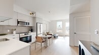 Located on Santa Monica Boulevard in the heart of West Los Angeles, this thoughtfully designed unit offers a clean, contemporary aesthetic throughout. Light wood-tone flooring flows continuously across the open-plan living, dining, and kitchen area, creating a cohesive and airy feel. Large windows and a glass-paneled balcony door flood the living space with natural light while providing views of the surrounding neighborhood. The balcony offers a comfortable outdoor retreat with seating. The kitchen is well-appointed with floor-to-ceiling white cabinetry, a tiled backsplash, stainless steel appliances including a dishwasher, range, microwave, and refrigerator, and a gold-accented faucet at the sink. A compact dining area with a marble-top table sits adjacent to the kitchen. The bedroom is serene and well-proportioned, featuring light-filled windows, light wood flooring, and generous closet access. The bathroom is finished with large-format terrazzo-style floor tiles, a wood-toned vanity, a backlit arched mirror, and a shower-tub combination. Throughout the unit, a neutral white and warm wood palette creates a calm, modern ambiance suited to urban living in West Los Angeles.