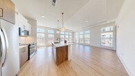 Located at 2124 American Industrial Way in Chamblee, GA, this well-appointed 2-bedroom, 2-bathroom residence offers a thoughtfully designed single-floor layout filled with natural light. The open-concept kitchen and living area is the heart of the home, showcasing soaring ceilings, wide-plank light hardwood flooring, and an expansive wall of floor-to-ceiling windows that bathe the space in sunlight. The kitchen is outfitted with stainless steel appliances, white upper cabinetry, wood-toned lower cabinetry, a white subway tile backsplash, and a large center island with quartz countertops and pendant lighting overhead. The generous living area extends seamlessly from the kitchen, offering open views through the oversized windows. Both bedrooms feature plush carpeting, tall windows with transom panes, and dedicated closets with built-in wire shelving for ample storage. The primary bathroom includes a glass-enclosed shower and a sleek single-vanity with quartz countertop, while the secondary bathroom features a full tub-shower combo and an extended double vanity with a framed mirror. Clean lines, a neutral palette, and consistent modern finishes create a cohesive and inviting ambiance throughout the entire residence.