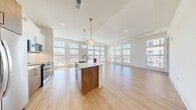 Located at 2124 American Industrial Way in Chamblee, GA, this well-appointed 2-bedroom, 2-bathroom residence offers a thoughtfully designed single-floor layout filled with natural light. The open-concept kitchen and living area is the heart of the home, showcasing soaring ceilings, wide-plank light hardwood flooring, and an expansive wall of floor-to-ceiling windows that bathe the space in sunlight. The kitchen is outfitted with stainless steel appliances, white upper cabinetry, wood-toned lower cabinetry, a white subway tile backsplash, and a large center island with quartz countertops and pendant lighting overhead. The generous living area extends seamlessly from the kitchen, offering open views through the oversized windows. Both bedrooms feature plush carpeting, tall windows with transom panes, and dedicated closets with built-in wire shelving for ample storage. The primary bathroom includes a glass-enclosed shower and a sleek single-vanity with quartz countertop, while the secondary bathroom features a full tub-shower combo and an extended double vanity with a framed mirror. Clean lines, a neutral palette, and consistent modern finishes create a cohesive and inviting ambiance throughout the entire residence.