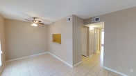 This single-story residence offers a clean, functional layout designed for comfortable everyday living. The interior is finished with light-colored ceramic tile flooring throughout, lending a bright and cohesive feel to the space. Neutral beige-toned walls complement the overall palette, creating a calm and understated ambiance.

The main living area features a ceiling fan with integrated lighting, providing both air circulation and illumination. A distinctive recessed niche is built into the dividing wall, offering a decorative display space that adds architectural character to the room. HVAC vents are positioned thoughtfully across the ceiling to ensure consistent climate control throughout.

A hallway connects the living area to the rest of the home, where built-in open shelving lines the corridor wall — a practical feature ideal for storage or display. Natural light filters in through a glazed door or window visible at the end of the hallway, enhancing the sense of openness and depth.

The layout flows logically between spaces, with clearly defined transitions from the main living zone to the adjoining rooms. The overall design is straightforward and well-maintained, emphasizing practicality and ease of use throughout the single-floor footprint.