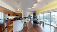 This well-appointed single-floor residence showcases a thoughtfully designed open-concept layout that seamlessly connects the kitchen, dining, and living areas. The kitchen is outfitted with warm wood cabinetry, dark granite countertops, a tile backsplash, and stainless steel appliances. A curved white breakfast bar with pendant lighting above serves as a functional divider between the kitchen and the main living space. Track lighting runs the length of the open area, ensuring consistent illumination throughout.

The dining area accommodates a full-sized table and is positioned near large windows that invite natural light and offer outdoor views. A fireplace anchors the adjoining living space, which features hardwood flooring throughout the common areas. A separate sitting room provides additional lounge space with its own track lighting.

The bedrooms are carpeted and offer ample closet storage, with ceiling fans providing comfort. One bedroom features bunk beds and a playful nautical theme. Bathrooms include a glass-enclosed tile shower with modern chrome fixtures. A hallway connects the private rooms to the main living area, maintaining a clear and logical flow throughout the residence.