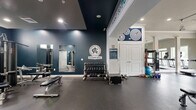 The Athletic Club at Florin Hill, located at 104 Merchant Ave in Mount Joy, PA, is a thoughtfully designed fitness facility that offers a comprehensive workout environment across a single, open floor. The space is divided into distinct functional zones, each catering to different aspects of physical training.

The cardio area features a row of modern treadmills and elliptical machines positioned facing large windows and glass double doors, flooding the space with natural light and providing views of the surrounding greenery. Track lighting runs along the ceiling, complementing the bright, open atmosphere.

Adjacent to the cardio zone, the strength training area is anchored by a full rack of dumbbells, a weight bench, and mirrored walls that visually expand the space. Bold navy-blue accent walls branded with the Athletic Club at Florin Hill logo add a strong, motivating aesthetic. Inspirational wall text reading "I Like to Move It / MOVE IT" reinforces the energetic ambiance throughout.

A functional training section offers stability balls, kettlebells, resistance bands, and yoga mats neatly organized on shelving units, supporting a wide variety of workout modalities. The durable rubber flooring throughout provides safety and comfort underfoot.

Crown molding and clean white architectural columns lend a refined, polished character to the space, balancing its athletic purpose with a welcoming, upscale feel.