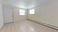 Located at 1127 Ward St in Chester, Pennsylvania, this single-floor space offers a straightforward and functional layout designed for comfortable everyday living. The interior is finished with light-toned ceramic tile flooring throughout, lending the space a clean, cohesive look that is both practical and easy to maintain. The main living area is bright and open, benefiting from natural light streaming in through two double-hung windows fitted with blinds. The walls are painted in a neutral off-white tone, creating a simple and versatile backdrop. A baseboard heating system runs along the exterior wall, ensuring efficient warmth during cooler months. The space features standard ceiling heights that contribute to an airy feel, and the minimal design keeps the focus on functionality. Electrical outlets are conveniently positioned along the walls, and the overall condition of the space appears well-maintained and move-in ready. The single-level layout makes the space accessible and easy to navigate, with no stairs to contend with. This property presents a clean, no-frills living environment in the Chester, PA area, suitable for those seeking a practical and comfortable place to call home.