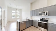 Located at 1225 Poinsettia Blvd in Denton, TX, this thoughtfully designed one-bedroom, one-bathroom residence makes excellent use of its single-floor layout. Soaring ceilings throughout create a striking sense of openness and volume well beyond what the footprint might suggest.

The open-concept kitchen and living area serves as the heart of the home. The kitchen is outfitted with gray shaker-style cabinetry extending to the upper walls, granite countertops, a subway tile backsplash, and a full suite of stainless steel appliances including a French door refrigerator, electric range, built-in microwave, and dishwasher. A peninsula with an undermount sink adds functional counter space and encourages an easy flow into the living area. Light wood-style flooring and a ceiling fan complete this shared space.

The bedroom is generously proportioned, featuring plush carpeting, tall ceilings, and large windows with transom panels that flood the room with natural light and offer views of the surrounding neighborhood.

The bathroom is well-appointed with a dark navy vanity topped with granite, a large mirror, light wood-style flooring, a soaking tub, and a separate shower. Additional conveniences include two closets, a dedicated pantry, and in-unit laundry, rounding out a highly functional and modern living space.