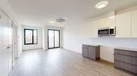 Located at 125 South Harrison Street in East Orange, NJ, this modern one-bedroom, one-bathroom apartment offers a thoughtfully designed layout with contemporary finishes throughout. The open-concept kitchen and living area serves as the heart of the home, featuring light wood-tone luxury vinyl plank flooring, crisp white walls, and a ceiling-mounted HVAC unit. The kitchen is outfitted with high-gloss white upper cabinetry, gray wood-toned lower cabinets, a subway tile backsplash, stainless steel appliances including a built-in microwave and dishwasher, and a stainless steel sink. Sliding glass doors lead to a private balcony, filling the living space with natural light and providing outdoor views. The bedroom is a bright, well-proportioned retreat with a large black-framed window overlooking the surrounding neighborhood. Two closets offer generous storage, one of which features built-in wire shelving and hanging rods. The bathroom is finished with a sleek white floating vanity with integrated sink, a mirrored medicine cabinet with built-in lighting, and a full bathtub with a glass panel enclosure. A separate utility room rounds out the functional layout of this clean, move-in-ready residence.