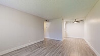 This efficiently designed single-floor, one-bedroom, one-bathroom unit offers a clean and modern aesthetic throughout. Light-toned wood-style flooring runs continuously across the living areas, bedroom, kitchen, and bathroom, creating a cohesive and contemporary feel. The living room is open and airy, featuring a ceiling fan with light fixture, a textured ceiling, and neutral warm-gray walls that complement the flooring. A hallway connects the main living area to the bedroom and bathroom, providing a practical and organized layout. The kitchen is thoughtfully appointed with crisp white shaker-style cabinetry, light countertops, a subway tile backsplash, and a full suite of stainless steel appliances, including a refrigerator, electric range, built-in microwave, and dishwasher. The bedroom offers a comfortable, private retreat with a large window fitted with blinds that allow natural light while maintaining privacy. The full bathroom is clean and functional, featuring a tub-shower combination, a toilet, and a vanity with mirror. A dedicated utility room provides added convenience and storage. Throughout the unit, neutral tones, clean lines, and updated finishes create a bright, move-in-ready living environment.