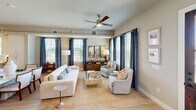 This well-appointed two-story home in Arlington, Texas offers four bedrooms and four bathrooms across two thoughtfully designed floors. The main level features an open-concept kitchen and living area bathed in natural light. The kitchen is a standout, boasting white shaker cabinetry, quartz countertops, stainless steel appliances, light hardwood flooring, and a large center island with seating — all illuminated by striking pendant lights. A powder bathroom on this level features neutral tones and elegant framed wall art. The living room is a comfortable, light-filled gathering space with multiple windows, warm neutral tones, and ample room for entertaining. Upstairs, the primary bedroom is a serene retreat featuring plush carpet, large windows with bold navy draping, and a ceiling fan. The en-suite primary bathroom impresses with a dual-sink vanity, grey cabinetry, marble-style tile flooring, and recessed lighting. The primary suite also includes a dedicated walk-in closet with built-in shelving and double hanging rods. Additional bedrooms are well-sized with access to shared bathrooms. A secondary living area upstairs provides flexible space with natural light and neighborhood views, completing this functional and stylish home.