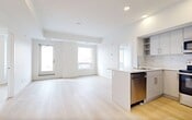 Located in the heart of downtown Edmonton at 104 Street NW, this well-designed 2-bedroom, 2-bathroom unit offers a clean, modern aesthetic throughout. Light-toned hardwood flooring flows seamlessly across the entire space, complementing the crisp white walls and creating a bright, airy atmosphere.

The open-concept kitchen and living area serves as the central hub of the unit. The kitchen is outfitted with flat-panel grey cabinetry, a marble-style tile backsplash, stainless steel appliances including a French door refrigerator, electric range, and built-in microwave, along with a generous island featuring a quartz countertop and undermount sink — ideal for both cooking and casual dining.

The primary bedroom benefits from multiple windows that frame expansive views of the Edmonton skyline and surrounding cityscape, filling the room with natural light. The second bedroom similarly features a window with outward city views, maintaining the bright character found throughout the unit.

Both bathrooms are finished with light wood-toned flooring and feature soaking tubs surrounded by grey subway tile, paired with modern white vanities and clean chrome fixtures.

The entrance provides a practical transition into the living space, with a dedicated closet for added storage. Recessed lighting and a neutral palette complete this contemporary, move-in-ready urban residence.