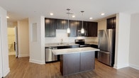 This single-floor residence in Castle Shannon, PA offers a thoughtfully designed layout with contemporary finishes throughout. The kitchen serves as a centerpiece of the home, showcasing rich dark cabinetry, light granite countertops, a center island with additional counter space, and a full suite of stainless steel appliances including a refrigerator, range, built-in microwave, and dishwasher. Pendant lighting above the island and recessed ceiling lights add warmth and functionality, while wood-style flooring ties the space together seamlessly.

The bedrooms feature plush wall-to-wall carpeting and natural light from well-placed windows. The primary bedroom connects to a spacious walk-in closet outfitted with wire shelving for organized storage. Two bathrooms mirror each other in style, each featuring dark vanity cabinetry, white countertops, large mirrors, chrome fixtures, and a distinctive black-and-white mosaic tile floor. The primary bathroom includes a double-sink vanity, while the second bathroom offers a tub-shower combination. Clean white walls and neutral tones throughout create a bright, cohesive ambiance that is both modern and welcoming.