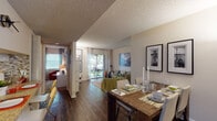 This single-story residence at 895 NW 213th Lane in Miami Gardens, Florida, offers a well-designed open floor plan that seamlessly connects the main living areas. Rich, dark wood-style flooring runs throughout the common spaces, lending a cohesive and polished look to the interior.

The kitchen is equipped with white cabinetry, granite-style countertops, black appliances, and a decorative mosaic tile backsplash, creating a functional and visually appealing workspace. A pass-through window connects the kitchen to the adjacent living and dining areas, enhancing the sense of openness.

The dining area accommodates a full-sized table and is accented by framed artwork, while the living room features neutral walls and direct access to a private outdoor patio through sliding glass doors, allowing natural light to pour in.

The bedrooms are carpeted for comfort and offer ample space, with large windows and closet storage. The bathroom is cleanly finished with tile surrounds, a tub-shower combination, wood-style flooring, and granite-topped vanity.

Additional flex space provides room for a reading nook or home office. The overall ambiance is warm and inviting, blending functional design with comfortable, everyday livability.