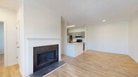 This single-floor residence features a clean, contemporary design highlighted by light wood flooring that runs consistently throughout every room, creating a cohesive and airy aesthetic. The open-concept living area serves as the heart of the space, anchored by a classic fireplace with a dark surround and white mantel. Large windows allow natural light to fill the living area, enhancing its bright and welcoming atmosphere.

The kitchen is well-appointed with gray cabinetry, white countertops, and a full suite of stainless steel appliances, including a refrigerator, range, microwave, and dishwasher. A peninsula provides additional counter space and connects the kitchen seamlessly to the living area.

The bedrooms are generously sized, each featuring the same warm wood flooring, neutral white walls, and windows that bring in natural light. The unit includes two bathrooms: one with a single vanity and tub-shower combination, and a second featuring an angled, corner-configured vanity with a quartz countertop, gray cabinetry with brushed nickel hardware, and a separate shower and soaking tub. The overall design is neutral, functional, and move-in ready.