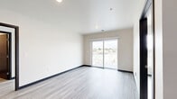 Located at 100 E National Ave in Milwaukee's Walker's Point neighborhood, this thoughtfully designed two-bedroom, four-bathroom unit offers a clean, contemporary aesthetic throughout its single-level floor plan. Light wood-style plank flooring flows consistently through the living areas and bedrooms, complemented by dark espresso-finished interior doors that add a striking contrast to the neutral, bright walls.

The open-concept kitchen serves as a central hub, featuring light maple cabinetry with matte black hardware, dark stone countertops, stainless steel appliances including a refrigerator, range with overhead ventilation, and dishwasher, plus a kitchen island with pendant lighting above — ideal for both cooking and casual dining.

Both bedrooms are well-proportioned, filled with natural light from large windows that frame urban Milwaukee views. The primary bedroom benefits from its own dedicated closet space. Two walk-in style closets with wire shelving systems provide generous storage throughout the unit.

The four bathrooms maintain a consistent, modern finish with light maple vanities, white countertops, stone-look tile flooring, and clean fixtures. Dark-finished door hardware and brushed nickel accents tie the design together cohesively. The overall ambiance is bright, minimal, and move-in ready.