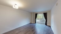 Located at 5409 Carlton Way in the heart of Los Angeles, CA 90027, this single-floor unit offers a clean, modern aesthetic throughout its well-appointed layout. Rich, hardwood-style plank flooring flows seamlessly across the living and dining areas, lending warmth and visual continuity to the space. The living room is bright and open, anchored by a large sliding glass door framed by dark grommet curtains that invite natural light and provide views of lush greenery outside. The galley-style kitchen is thoughtfully designed with crisp white shaker cabinetry, sleek quartz countertops, light tile flooring, and a full suite of stainless steel appliances including a gas range, over-the-range microwave, and dishwasher. A pass-through peninsula connects the kitchen to the main living area, creating an open, communicative flow ideal for everyday living. A hallway leads to the bedroom and bathroom, maintaining a sense of privacy. The bathroom features a full tub and shower combination with stainless steel safety grab bars and clean white finishes throughout. Neutral wall tones and consistent ceiling-mounted lighting fixtures give the entire unit a cohesive, move-in-ready appearance. The space strikes a balance between functional design and comfortable living in a desirable Los Angeles neighborhood.