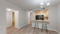 Located at 1800 Lakewood Dr in Phenix City, Alabama, this single-floor residence offers a thoughtfully updated interior with a cohesive, modern aesthetic. Light wood-look flooring runs throughout the entire space, creating a clean and consistent look from room to room.

The open-concept living and dining area is bright and welcoming, featuring a chandelier, textured ceiling, and large windows with blinds that allow ample natural light to fill the space. A secondary door provides additional outdoor access directly from the living area.

The kitchen is a standout feature, showcasing white shaker-style cabinetry, granite countertops with a matching backsplash, and black appliances including a refrigerator, range, microwave, and dishwasher. A peninsula with bar seating and a pendant light overhead connects the kitchen to the living space, making it ideal for casual dining and entertaining.

The bedrooms are generously sized, each equipped with ceiling fans and windows that bring in natural light. One bedroom features a large bank of windows, enhancing its airy feel.

The bathroom includes a tiled tub-and-shower combination, a granite-topped vanity with white cabinetry, and wood-look tile flooring that ties in with the rest of the home. A hallway with built-in storage connects the main living areas to the private spaces of the home.