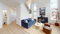Located in Herriman, Utah, this contemporary two-story home offers three bedrooms, four bathrooms, and a thoughtfully designed layout spread across two floors. The exterior presents a clean, modern farmhouse aesthetic with board-and-batten siding, a dark front door, an attached garage, and neatly landscaped grounds framed by mountain views in the distance.

The main floor hosts an open-concept kitchen and living area. The kitchen is well-appointed with white shaker cabinetry, quartz countertops, stainless steel appliances, a subway tile backsplash, and a central island with bar seating illuminated by pendant lighting. The adjoining living room impresses with soaring double-height ceilings, tall windows that flood the space with natural light, light wood-tone flooring, and a sleek fireplace as a focal point.

Upstairs, the generously sized primary bedroom features plush carpet, access to a dedicated closet, and a refined en-suite bathroom with dual sinks, quartz countertops, shaker-style vanity cabinetry, and elegant marble-look tile flooring. Two additional bedrooms and further bathrooms are also located on the upper floor, along with a conveniently placed laundry room equipped with a full-size washer and dryer and overhead shelving storage.