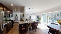This thoughtfully designed single-floor residence offers a seamless blend of comfort and modern style throughout its well-organized layout. The open-concept kitchen serves as the heart of the home, featuring rich dark wood cabinetry, granite countertops, a green subway tile backsplash, and a full suite of stainless steel appliances including a gas range, microwave, dishwasher, and refrigerator. A built-in breakfast bar with pendant lighting provides additional seating and connects the kitchen to the living areas. The living room is bright and inviting, benefiting from large sliding glass doors that open to a private balcony and allow abundant natural light to fill the carpeted space. A separate dining area with hardwood-style flooring offers a dedicated space for meals, also with direct access to the outdoors. The bedrooms are generously sized with soft carpet flooring, ceiling fans, and ample closet space, providing a restful retreat. The bathroom is clean and classic, finished with large-format neutral tiles surrounding a full soaking tub. Throughout the residence, a consistent palette of whites and warm wood tones creates a cohesive, modern aesthetic.