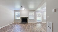This two-floor residence offers a well-organized layout with distinct living, kitchen, and sleeping areas across its two levels. The main living area is a welcoming, open space highlighted by a tile-surround fireplace flanked by multiple windows with white blinds, allowing natural light to fill the room. Wood-look flooring runs throughout the main level, providing a warm, cohesive aesthetic, while a textured ceiling adds architectural character. A staircase with carpeted treads connects the two floors seamlessly.

The kitchen is efficiently designed in a galley configuration, featuring white cabinetry, white quartz-style countertops, a subway tile backsplash, and a full suite of stainless steel appliances including a refrigerator, electric range, and built-in microwave. A stainless steel sink with a modern faucet completes the space.

Upper-level bedrooms are finished with plush carpet and offer generous closet space with sliding panel doors. Natural light reaches the bedrooms through windows with outdoor tree views, and baseboard heating ensures comfort year-round.

The bathroom is clean and functional, featuring a white vanity with ample cabinet storage, a large mirror, wood-look tile flooring, and a full bathtub with a bright white surround. The overall palette of neutral grays and whites gives the entire space a fresh, move-in-ready appearance.