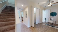 Located at 6337 Grand Blvd in New Port Richey, Florida, this two-story home presents a clean, neutral aesthetic across both levels. The entry foyer sets an organized tone with light wood-style flooring, recessed lighting, and access to a walk-in closet, establishing a welcoming transition into the main living areas.

The living room features the same wood-style flooring, a ceiling fan, and ample natural light from side windows. It flows naturally into a dining area distinguished by vaulted ceilings, a classic chandelier, and sliding glass doors that open to a balcony with outdoor views—bringing in generous natural light.

The kitchen is well-appointed with white shaker-style cabinetry, granite countertops, a subway tile backsplash, and a full suite of stainless steel appliances, including a side-by-side refrigerator, electric range, and built-in microwave.

Upstairs, the bedroom offers plush carpeting, multiple windows with outdoor views, and a relaxed, airy atmosphere. The bathrooms are finished with tile flooring, white vanities with quartz countertops, and framed glass-door showers with subway tile surrounds. A dedicated laundry room with full-size washer and dryer and overhead shelving adds functional convenience to the layout.